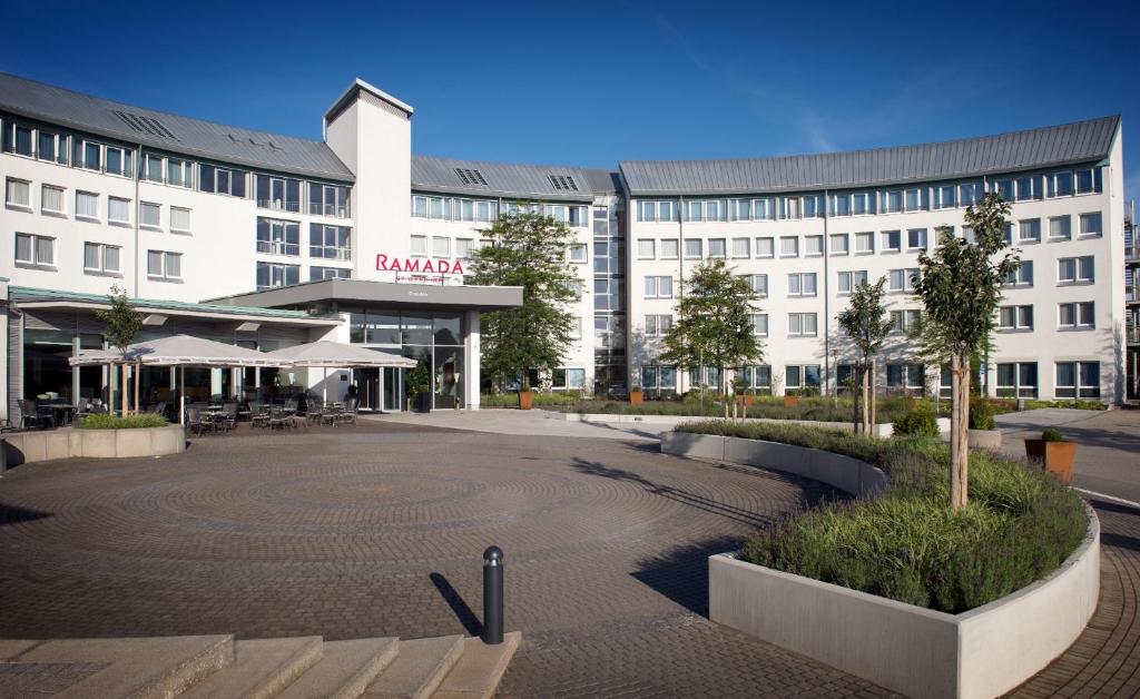 a large white building with a courtyard in front of it at Ramada by Wyndham Dresden in Dresden