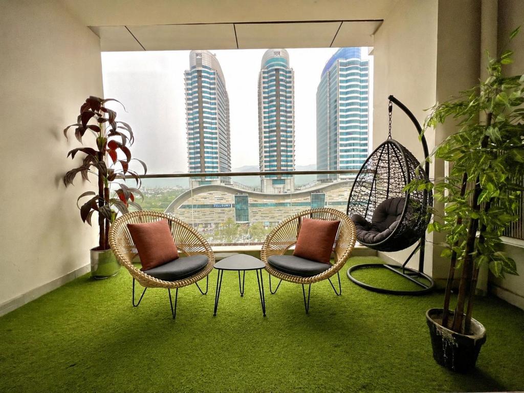 a balcony with three chairs and a table and a window at ELYSIUM TOWER Luxury Hotel Apartments Facing Centaurus Mall Islamabad in Islamabad
