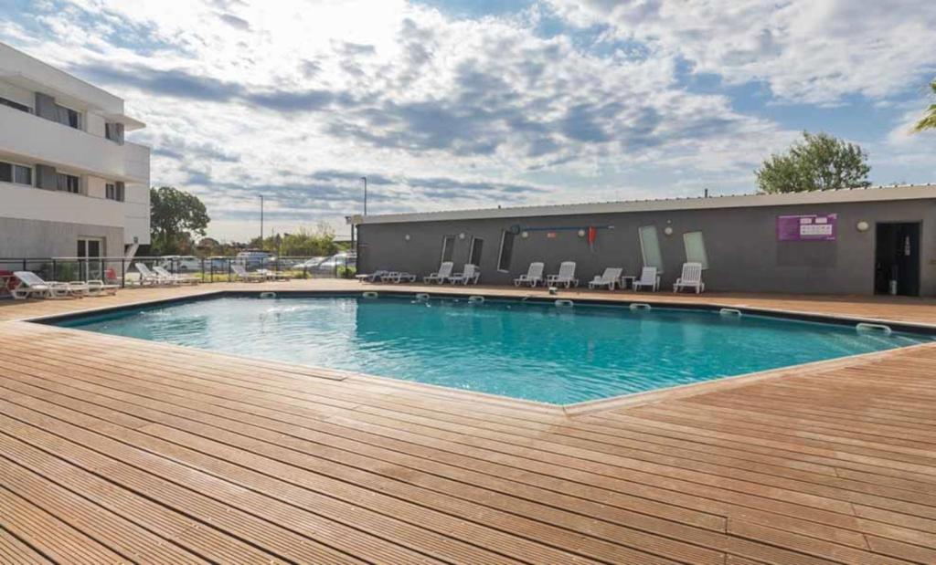 a swimming pool on a deck next to a building at Vacancéole - Le Terral - Montpellier Sud in Saint-Jean-de-Védas
