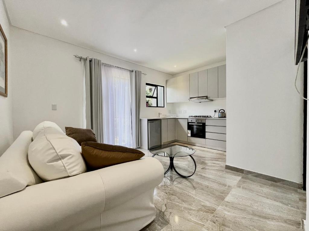 a living room with a white couch and a kitchen at Number 12, Jadde apartments in Sandton