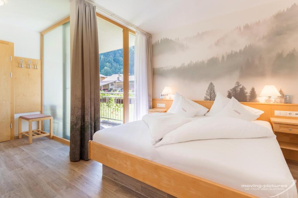 a bedroom with a large bed and a large window at Hotel Silbertal in Silbertal