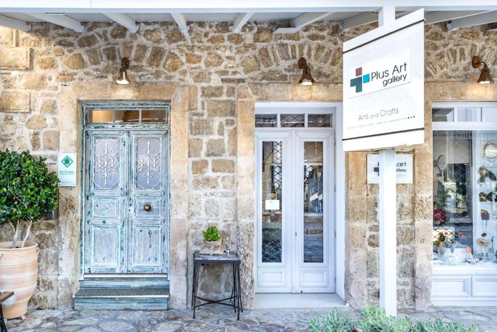 a store front with a blue door and a stone wall at Art Studios Gialova Navarino in Gialova
