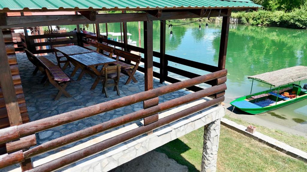 a deck with a table and a boat on the water at Laki House Skadar lake in Železnička Stanica Zeta
