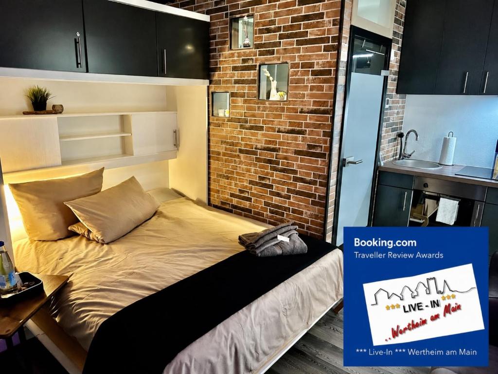 a bed in a small room with a brick wall at LIVE-IN Tiny Studiowohnung in Wertheim