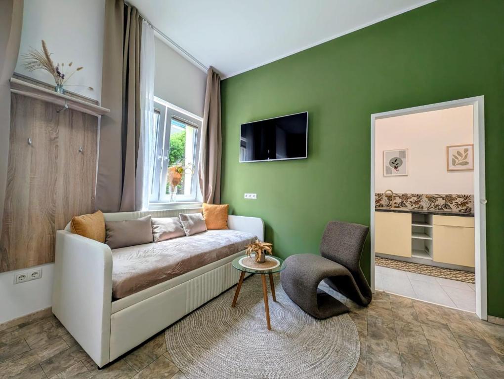a green living room with a couch and a chair at Aparthotel Neudörfl in Neudörfl