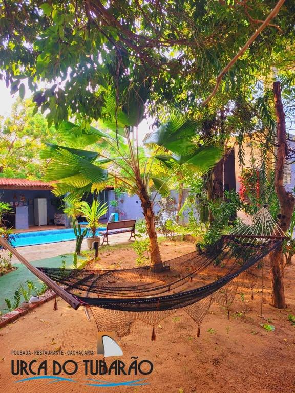 a hammock in front of a house with trees at Urca do Tubarão in Touros