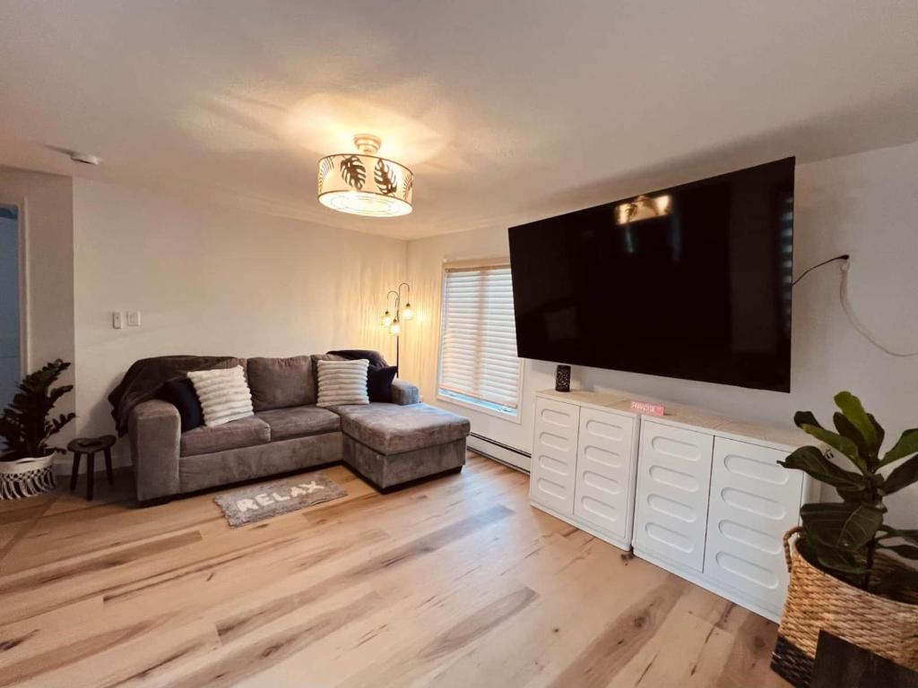 a living room with a couch and a flat screen tv at The SeveraLena, your Tawas Point destination! in East Tawas