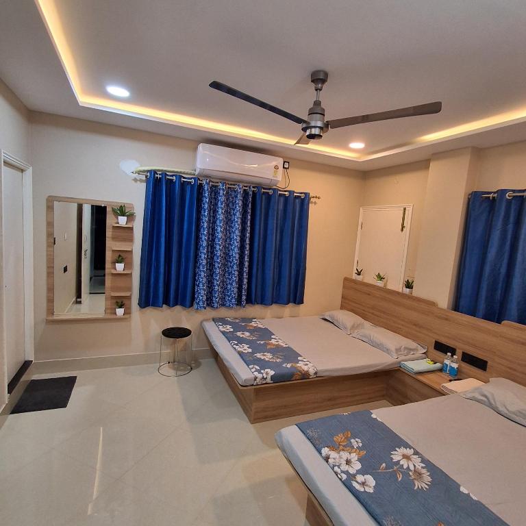 a bedroom with two beds and blue curtains at Royal Homestay Siliguri in Silīguri Junction