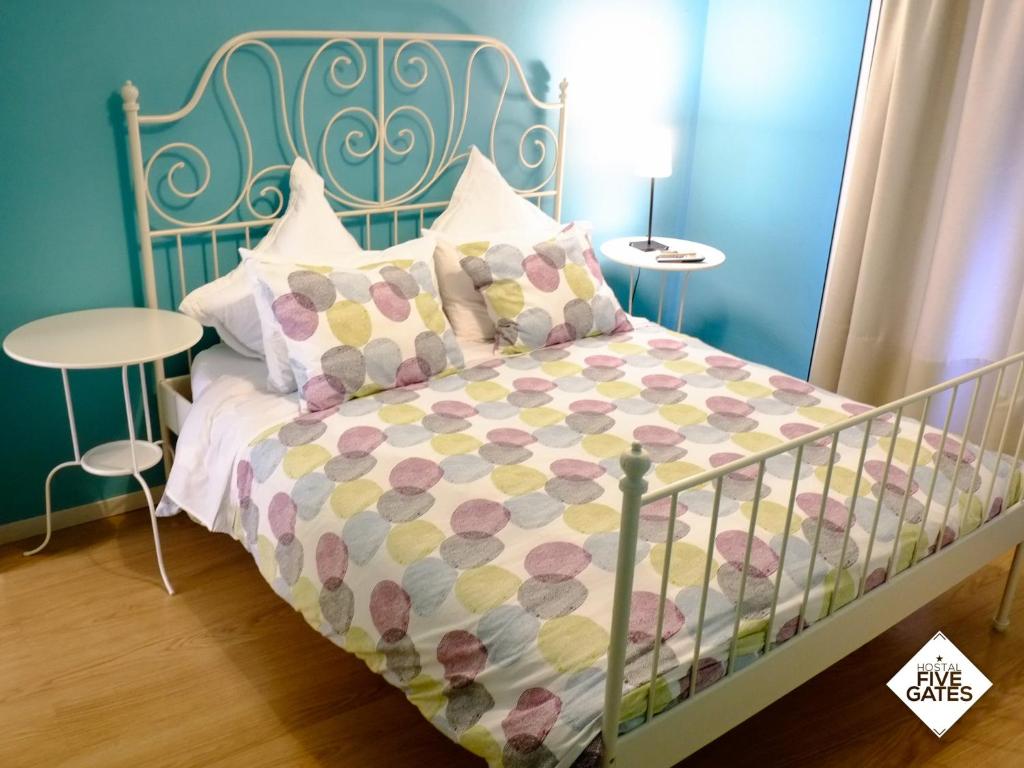 Dormitorio azul con cama con colcha y almohadas en Hostal Five Gates, en Osuna