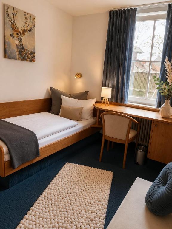 a bedroom with a bed and a desk and a window at Hotel zur Linde in Berghausen