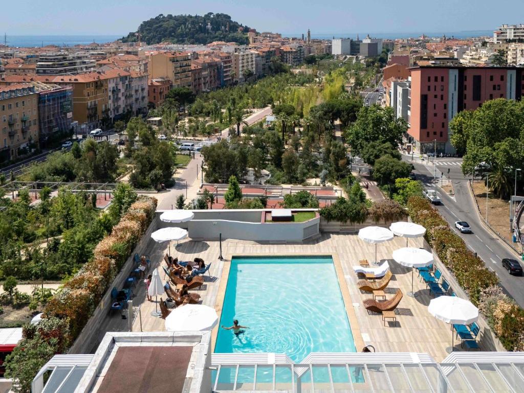 a view of a pool with umbrellas and a city at Novotel Nice Centre Vieux Nice in Nice