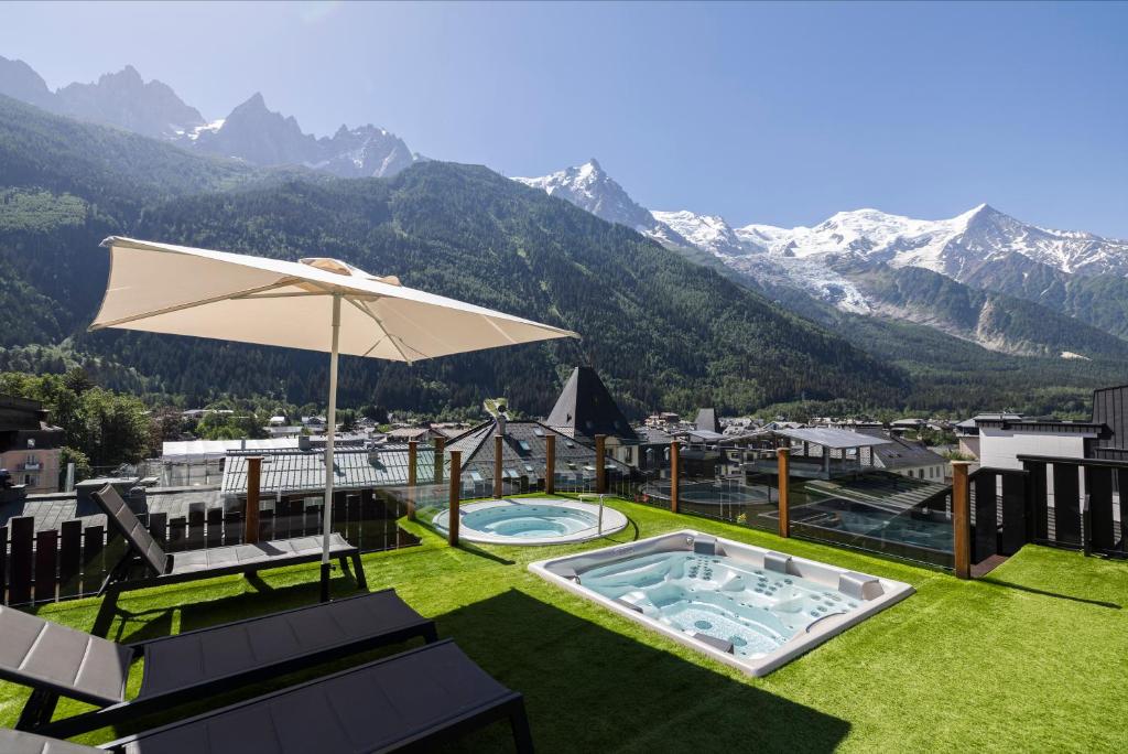 a patio with an umbrella and a swimming pool and mountains at Park Hotel Suisse & Spa in Chamonix