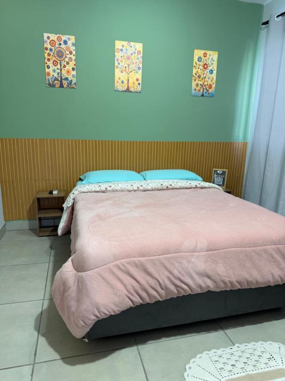a bed in a bedroom with a pink bedspread at Casa aconchegante in Timbó
