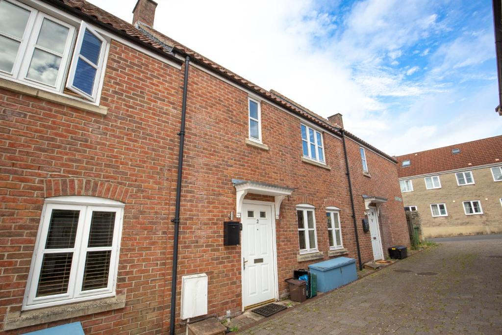 a brick building with a white door on a street at 2 Crown Barton in Glastonbury