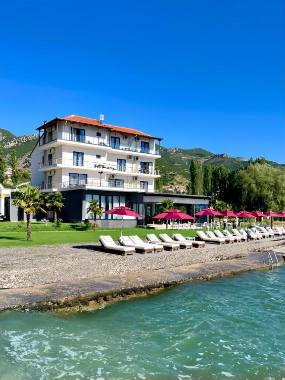a row of lounge chairs on a beach next to the water at Hotel Victoria in Pogradec