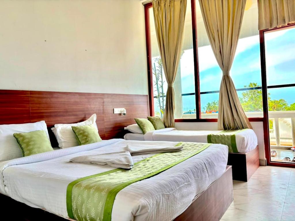 two beds in a room with large windows at La Couronne Seaview Resort in Pondicherry