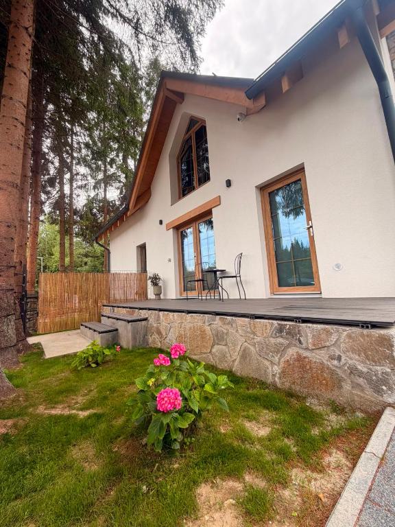 a house with a stone retaining wall and some flowers at Tiny Jazz in Gărâna