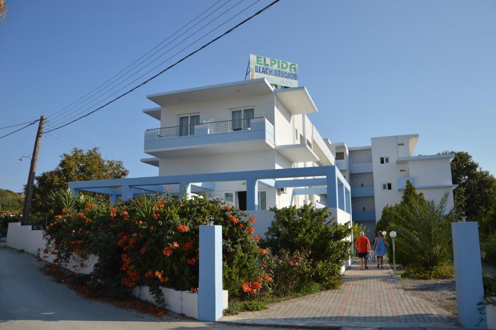 un edificio blanco con flores delante en Elpida Beach Studios en Faliraki