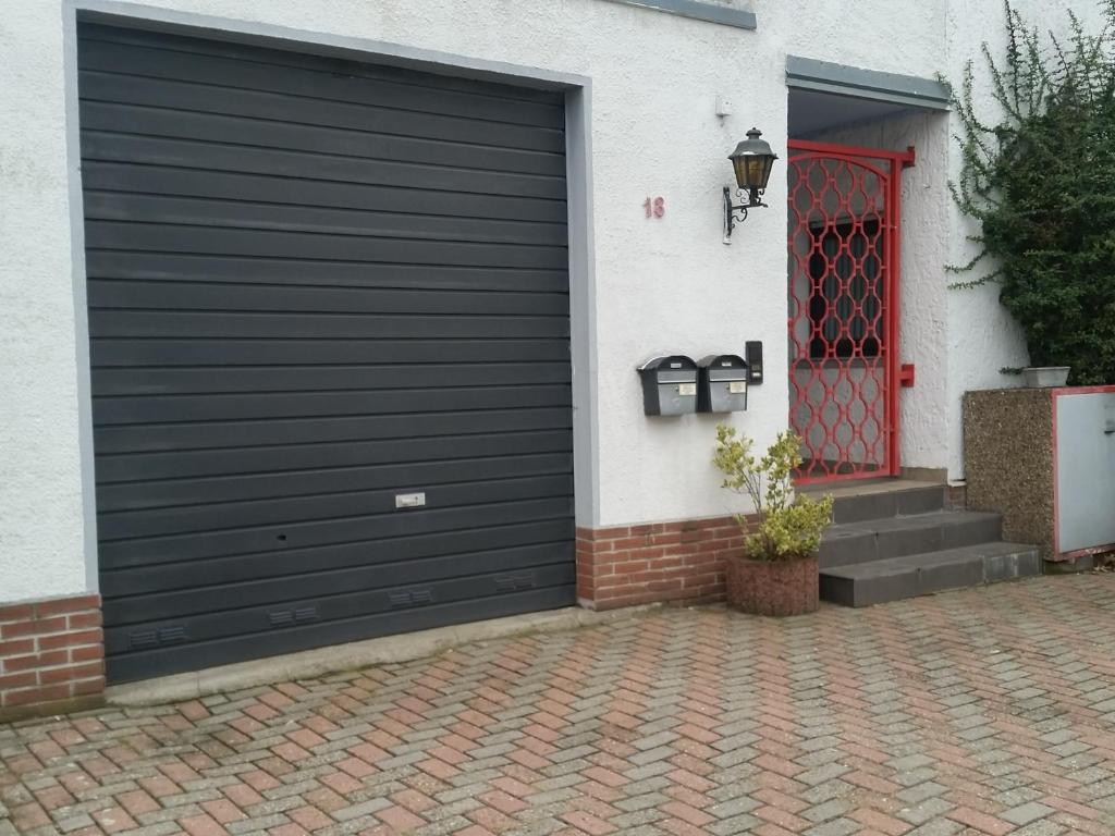 een zwarte garagedeur op een huis met een rode deur bij Haus Nähe Flughafen und Messe in Düsseldorf