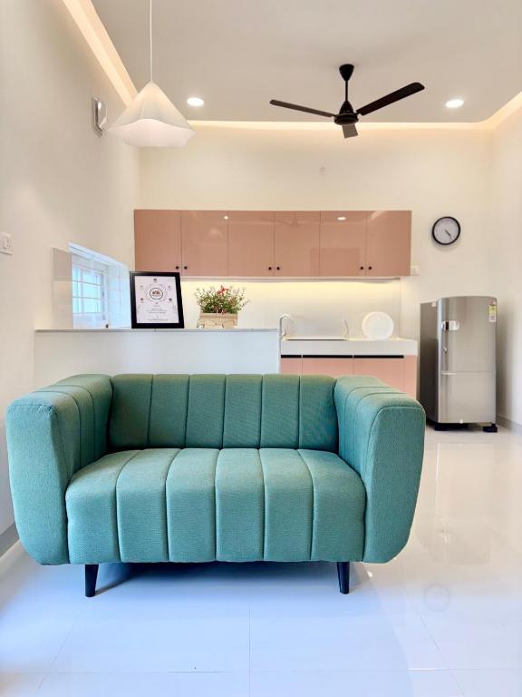 a blue couch in a living room with a kitchen at Meadows Homestay Elite in Madurai