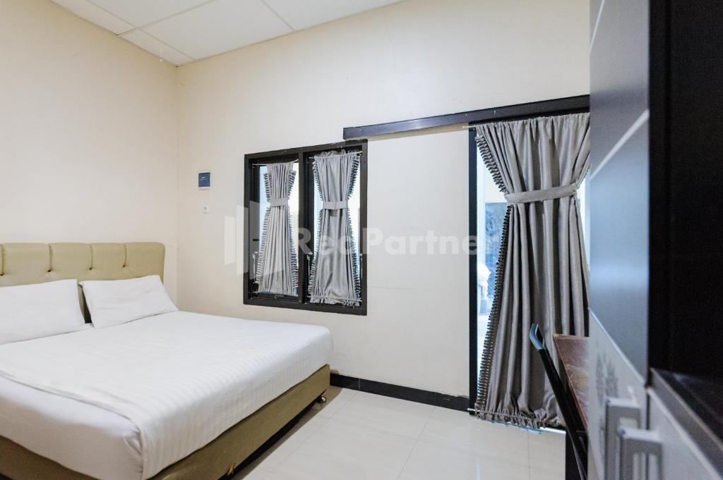 a bedroom with a bed and a large window at Wisma Merdeka Syariah RedPartner in Palembang