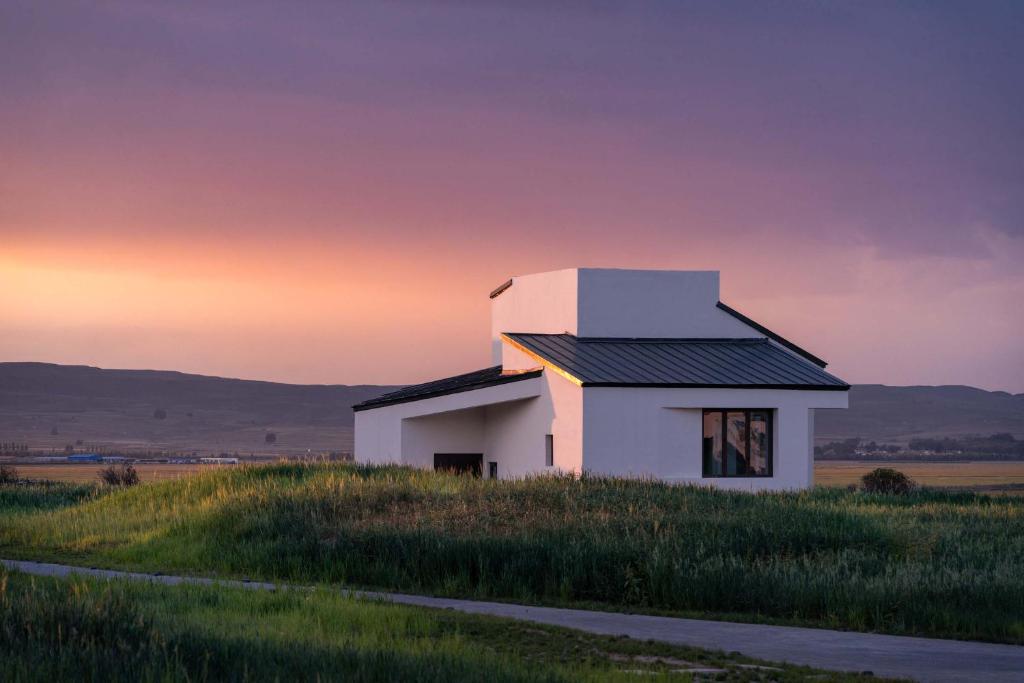 a white house on top of a grassy field at Things grow in their native land in Ulanqab