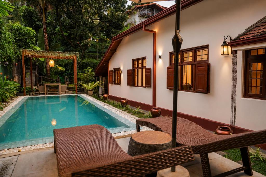 a house with a swimming pool and a table and chairs at Colonial Residence Kandy Boutique Bungalow in Kandy