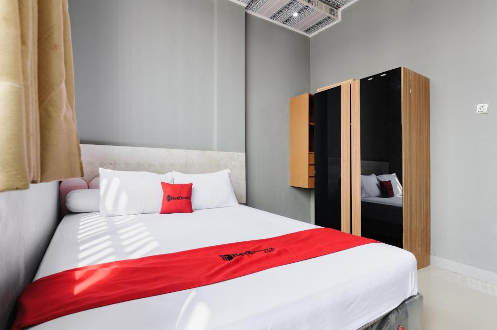 a bedroom with a white bed with a red blanket at RedDoorz Lotte near PTC MALL in Palembang