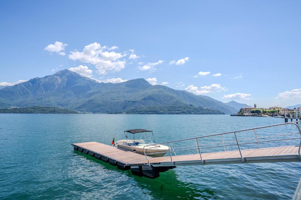 a boat on a dock on a lake with mountains at Sweet Memories-Gravedona 100m to Lake-Lake Como Escape in Gravedona