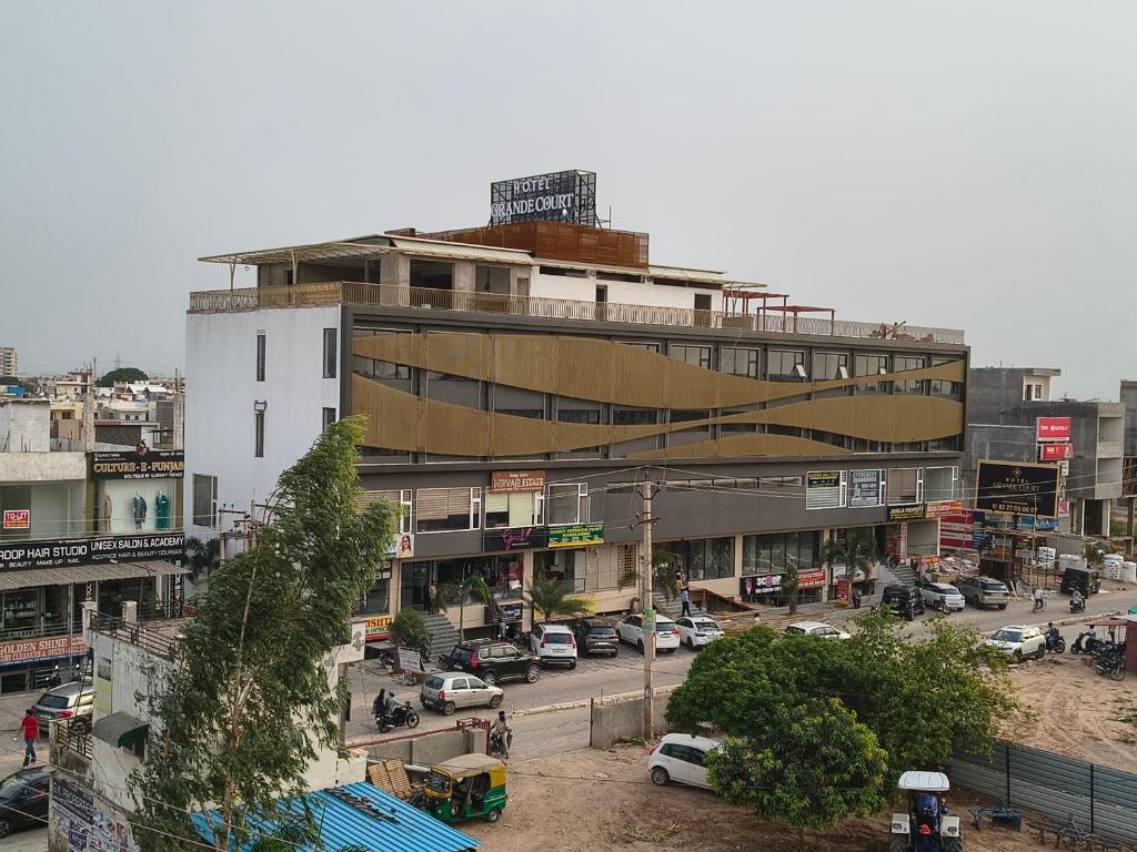 a large building with a parking lot in a city at Hotel Grande Court in Kharar