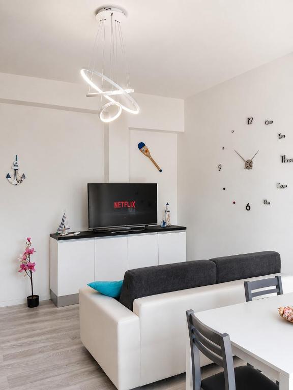 a living room with a white couch and a clock at Solution Timone - Appartamento al mare in Punta Marina