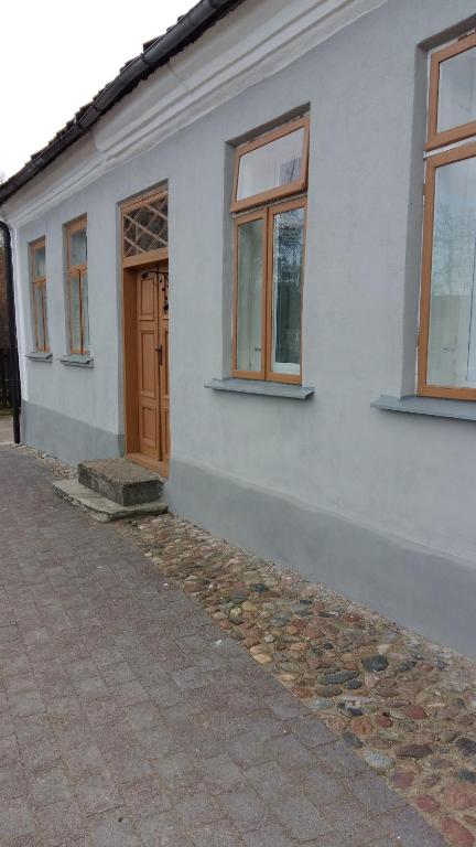 un edificio blanco con una puerta y ventanas marrones en Lauma en Kuldīga