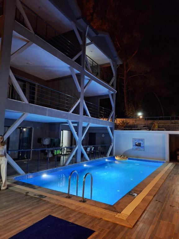 a person standing next to a swimming pool at night at MAİ Sarıgerme in Sarigerme