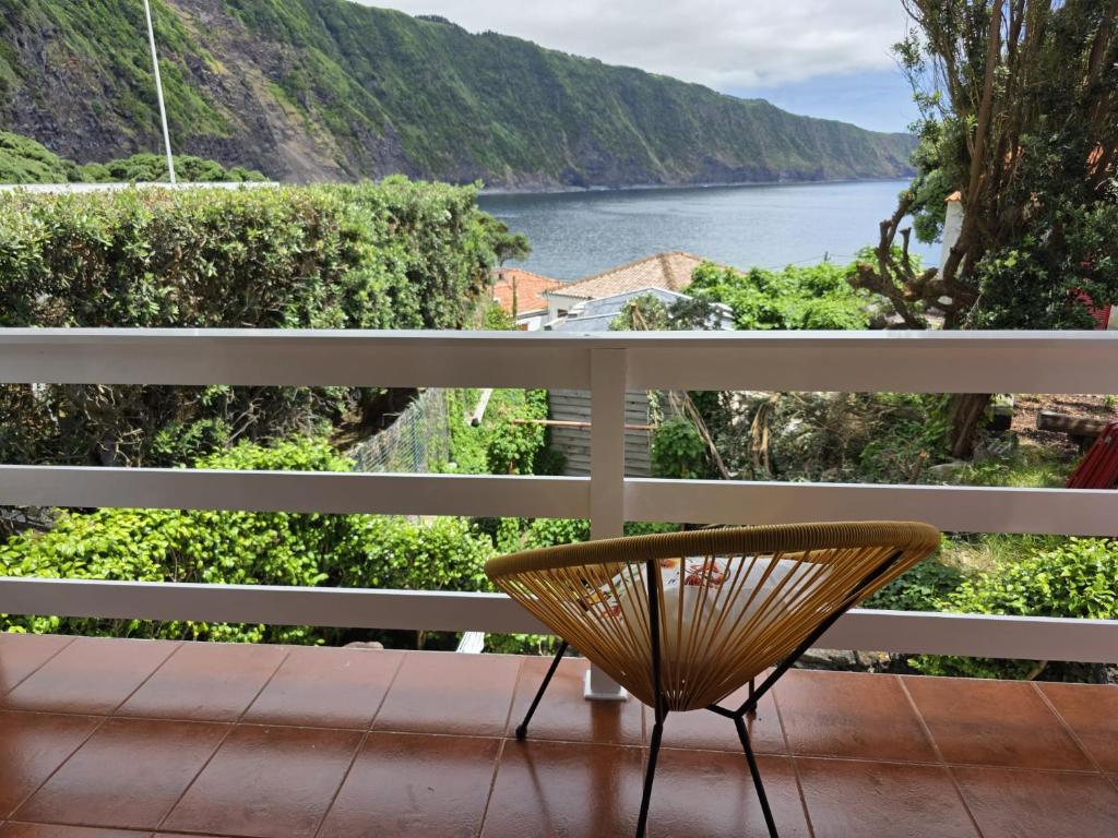 a chair on a balcony with a view of the water at Varadouro Cove House in Horta