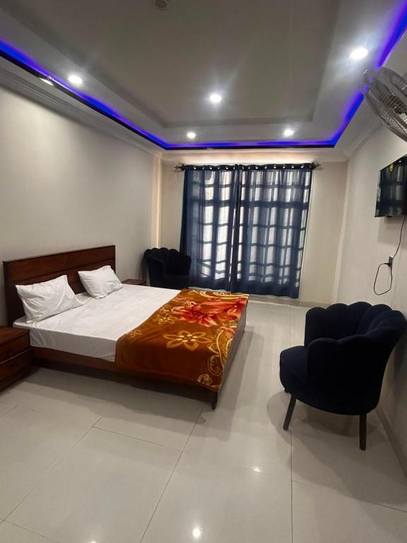 a bedroom with a bed and two chairs in it at Regal Heights in Bhurban