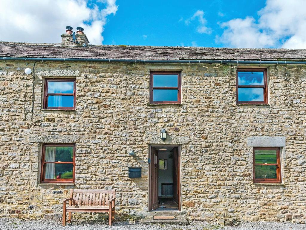 a stone house with a bench in front of it at 5 Swallowholm Cottages in Richmond