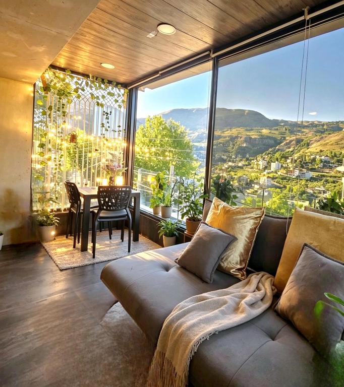 a living room with a couch in front of a large window at Farayayellowstone 1 bedroom with panoramic mountain view fit 4 in Bayn an Nuhūr
