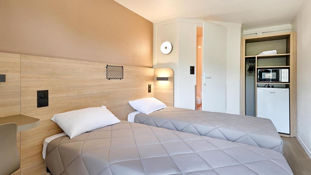 two beds in a small room with a kitchen at Premiere Classe Dreux in Dreux