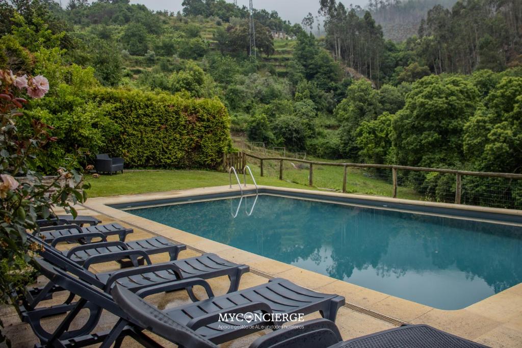a pool with chairs and a view of a mountain at Quinta do Moinho in Castelo de Paiva