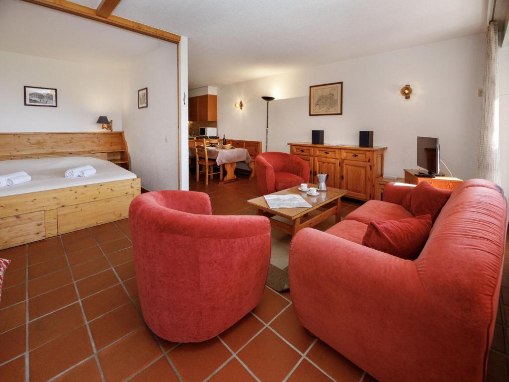 a living room with red chairs and a bed at Studio Terrasse Des Alpes 615 by Interhome in Vermala