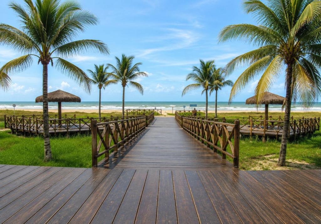 a wooden boardwalk to the beach with palm trees at Quarto Nômade Digital in Aracaju