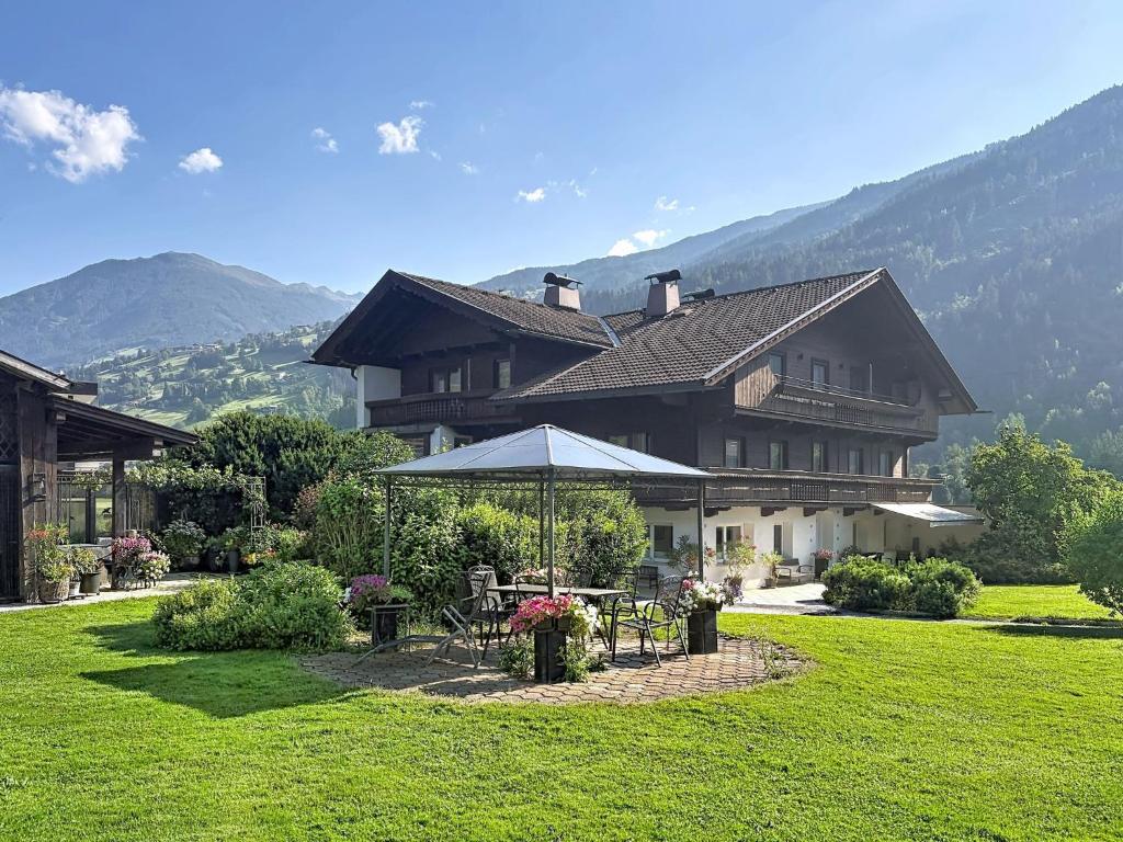 a large house with a table and an umbrella at Apartment Appartements Binderhof-1 by Interhome in Aschau
