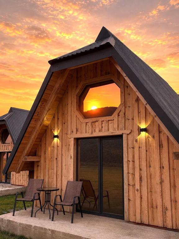a building with chairs and a table with a sunset at Alvearium Chalets in Žabljak