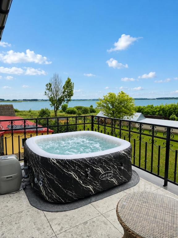 a hot tub on a patio with a fence at Szept Jeziora in Czechowizna