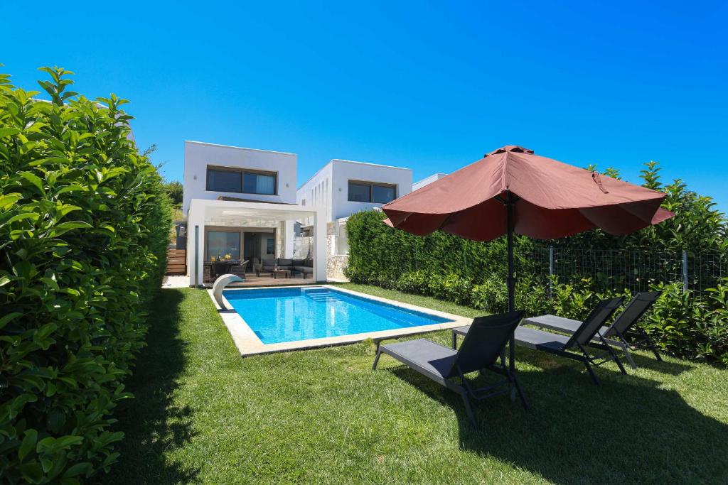 a house with a swimming pool and an umbrella at Villa Mare 2 - Private Pool, Sea View, Starlink, 4 Bdrms in Hanioti