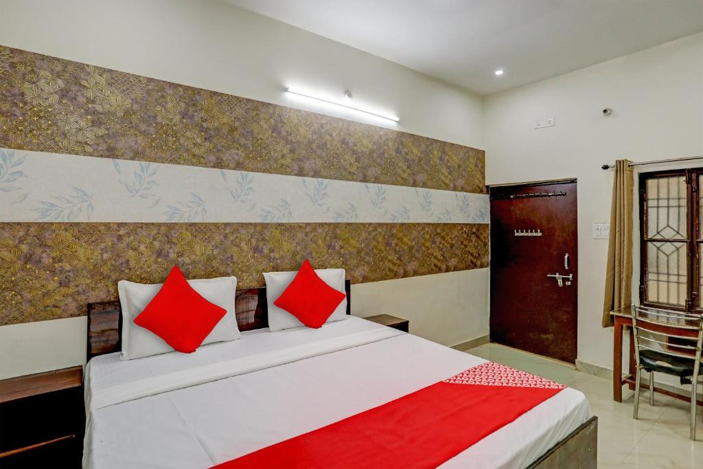a bedroom with a large bed with red pillows at Hotel O The Raghav Villa in Prayagraj