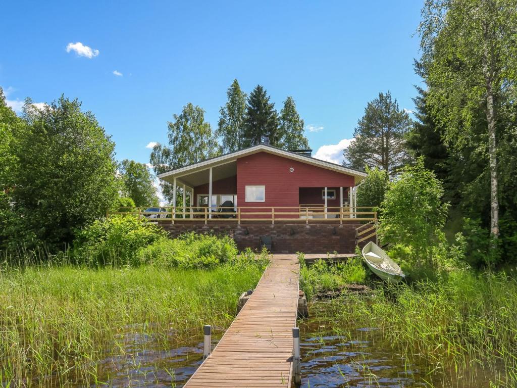 a red house with a dock and a boat on the water at Holiday Home Suvela by Interhome in Kukkola