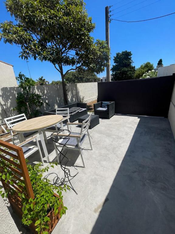 a patio with a table and chairs and a tree at T2 avec terrasse privative Berre-l'Étang in Berre-lʼÉtang