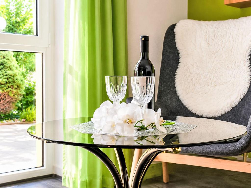 a glass table with a bottle of wine and two glasses at Apartment Siebers by Interhome in Sebnitz