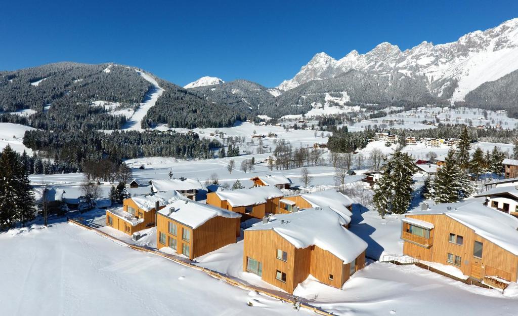 a village covered in snow with mountains in the background at Rittis Alpin Chalets Dachstein in Ramsau am Dachstein